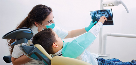 Dental hygienist showing a young boy an Xray of his teeth.
