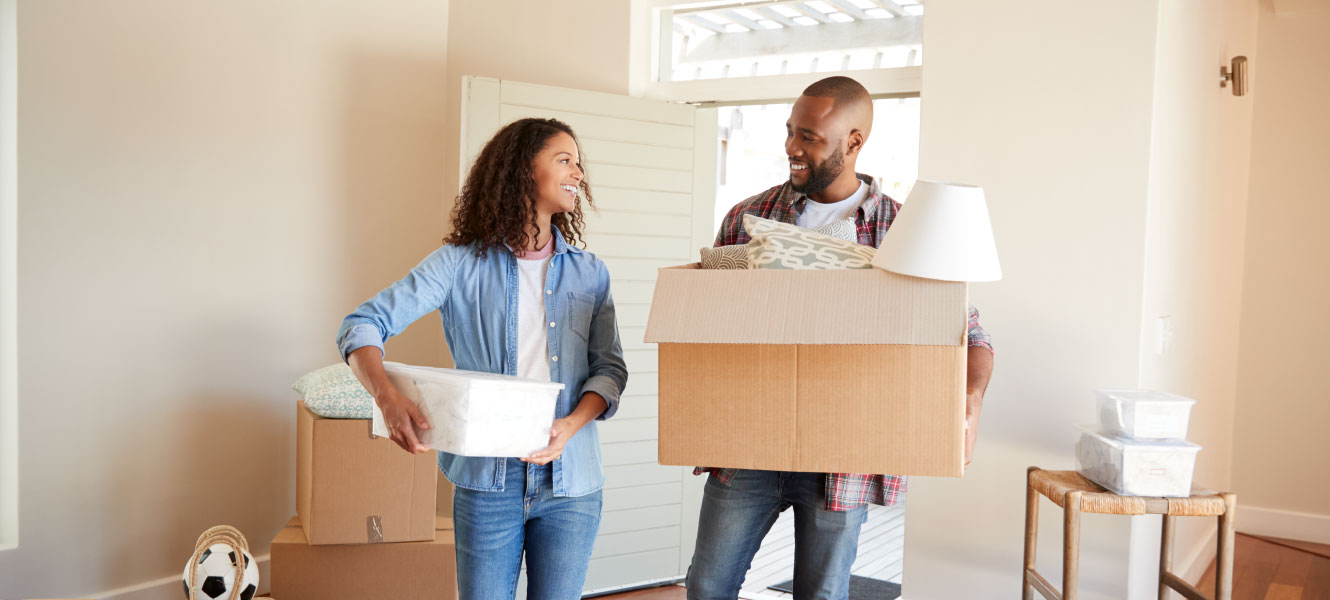 a couple moving boxes into their new home