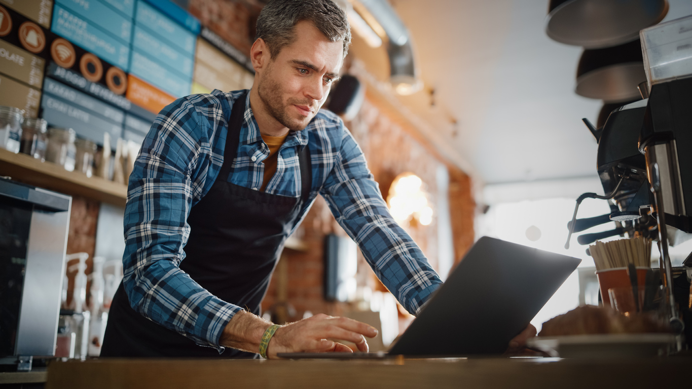 Coffee shop owner working on his laptop.