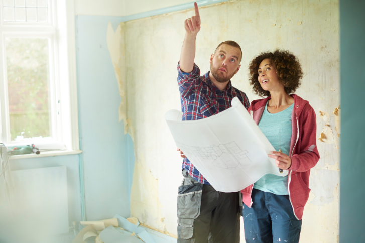 A man and woman working on a house.