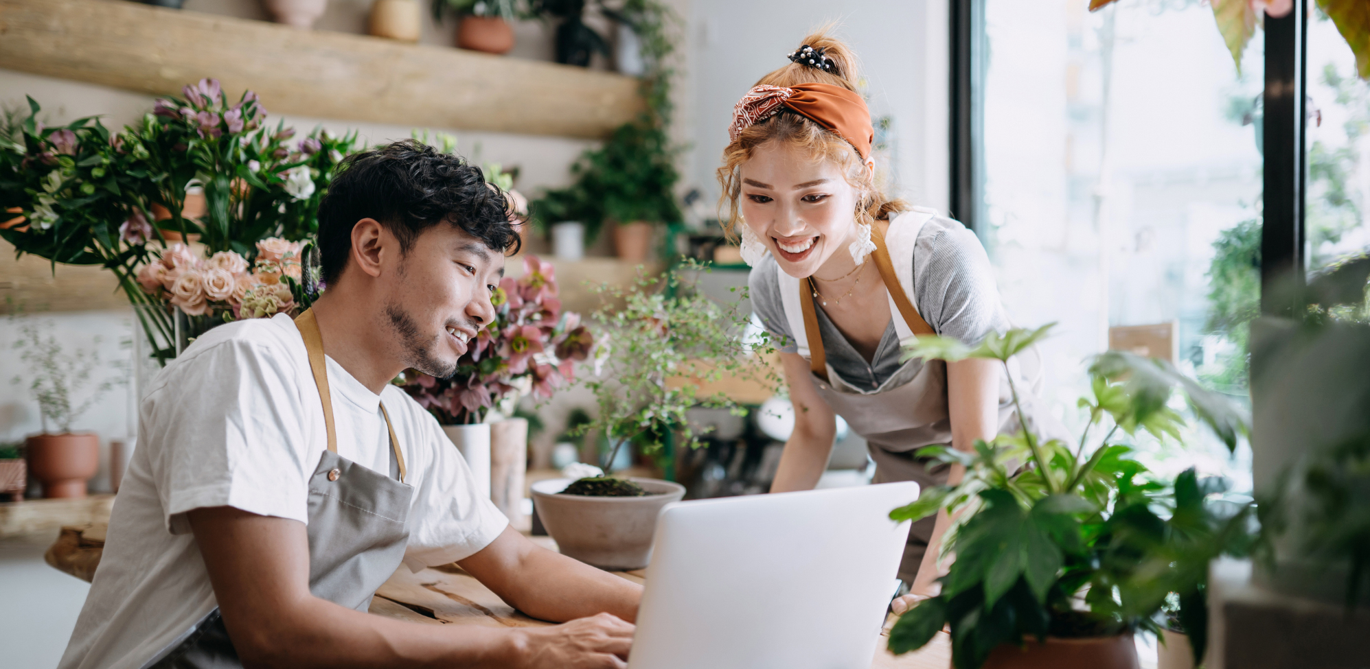 Coworkers smiling at laptop in garden

